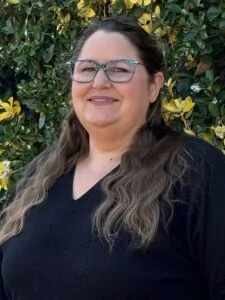 Female with long brown hair and colorful glasses