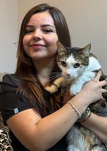 Female with long brown hair holding a black and brown cat